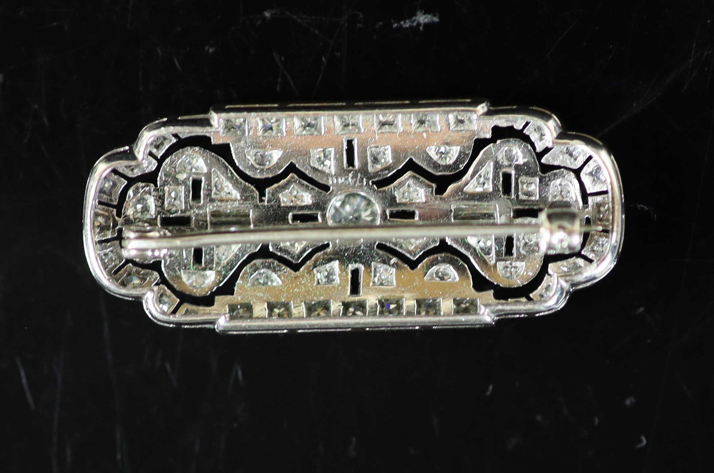 An Art Deco style pierced platinum, round and baguette cut diamond set shaped rectangular brooch